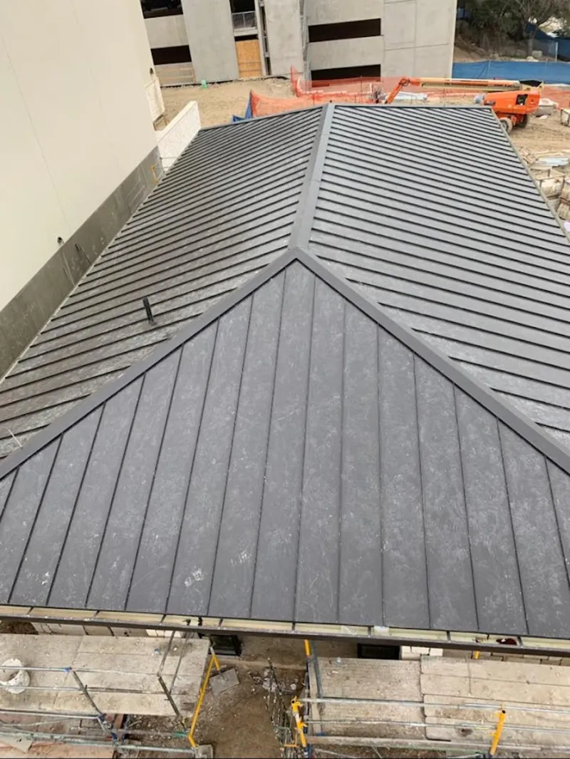 Commercial metal roof construction with crane equipment in Dennis